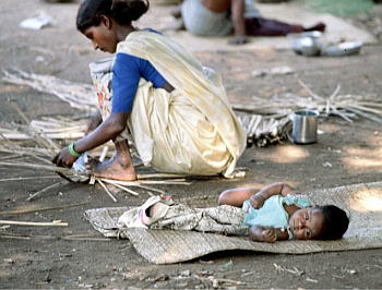 A woman worker concentrating on her work with her baby on her side in the southern Indian State of Tamil Nadu. The infant mortality rate for working women is higher particularly among those in the primary sector, a large proportion of whom are labourers.