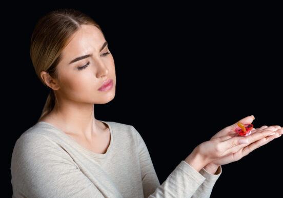Prohibition on child birth, infertility. Desperate woman looks at pacifier in hands Prohibition on child birth, infertility. Desperate woman looks at pacifier in hands, isolated on black background, studio shot